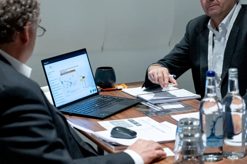 Mining industry professionals reviewing company information on a laptop during a private meeting